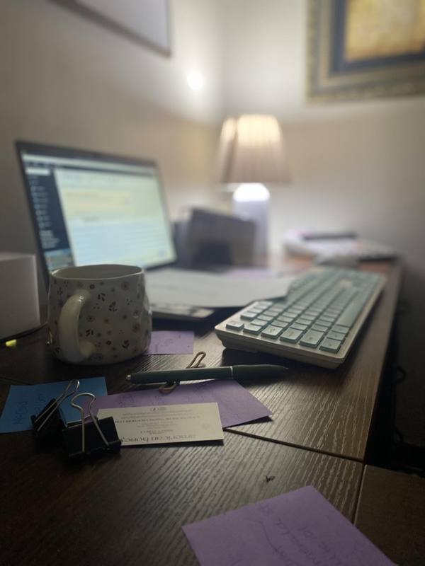 Dark moody desk workspace with laptop, keyboard, and lamp glow